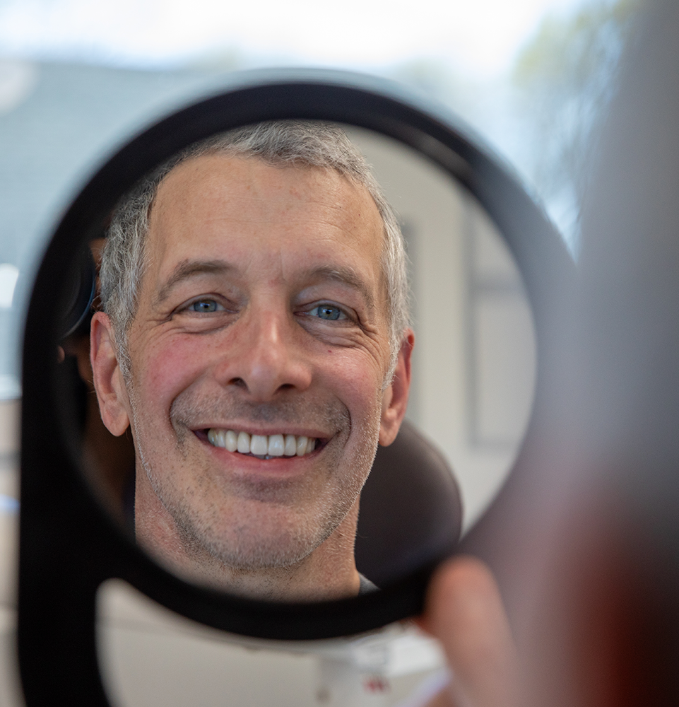 patient holding a mirror and smiling